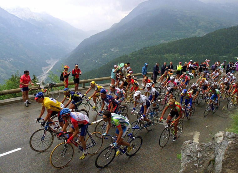 Overall leader Lance Armstrong of the U.S., left in yellow, and the rest of the pack climb Tamie pass during the ninth stage of the Tour de France cycling race between Le Grand-Bornand, French Alps, and Sestrieres in the Italian Alps Tuesday, July 13, 1999. (AP Photo/Laurent Rebours)